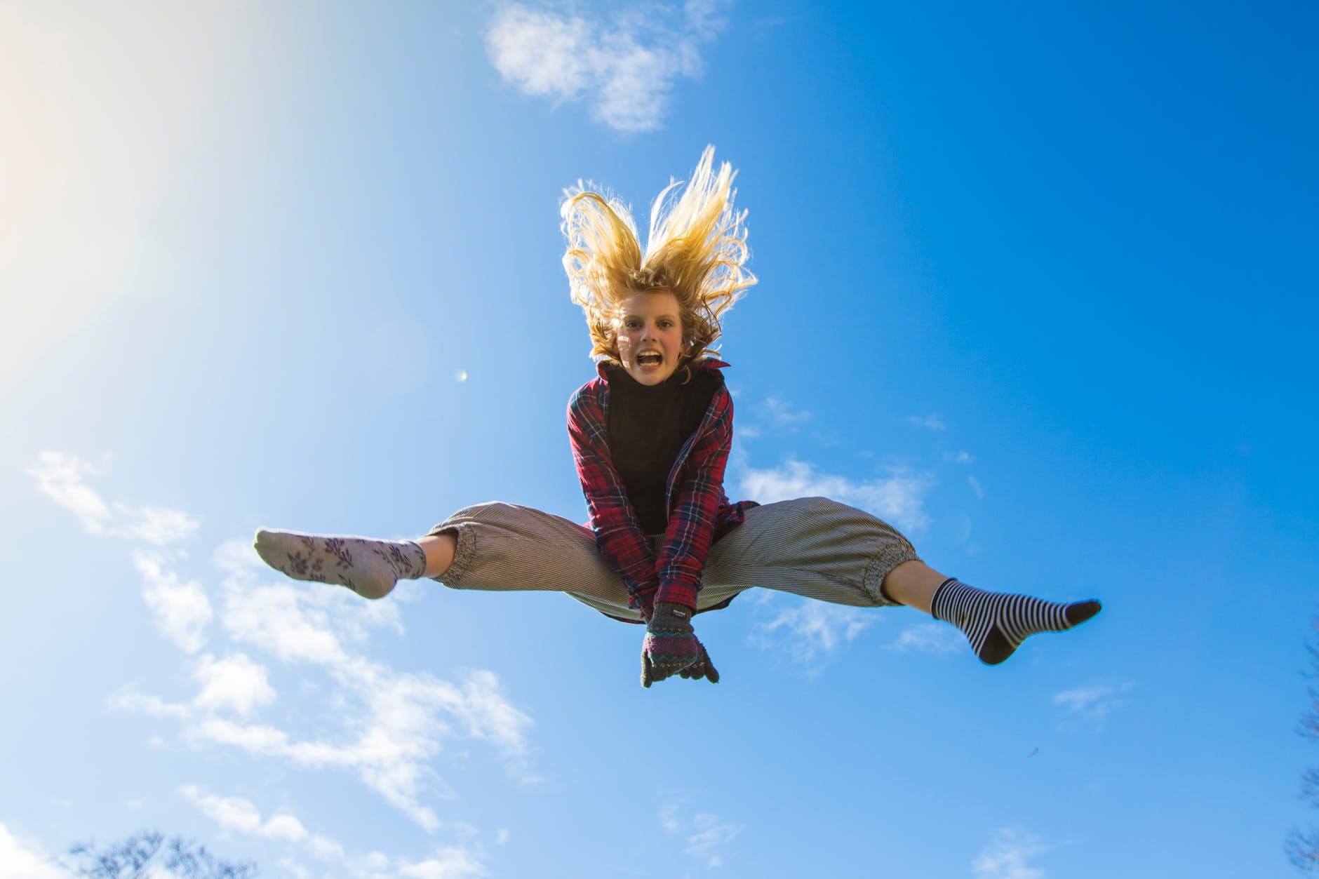 woman jumping under blue sky