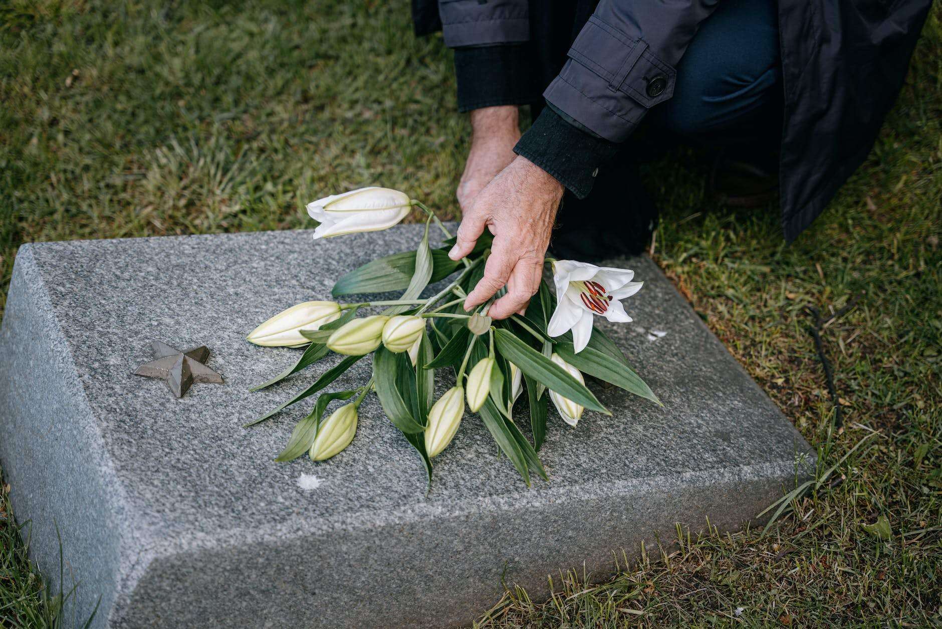 a person putting flowers on a headstone