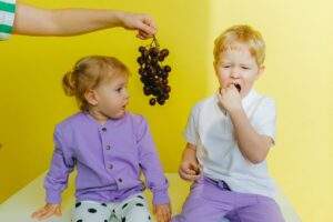 person holding grapes between boy and girl