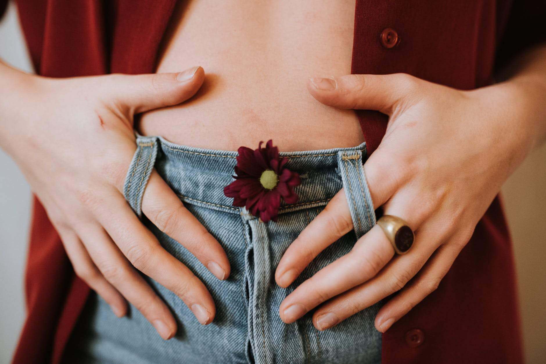 woman showing flower on hands and bare belly