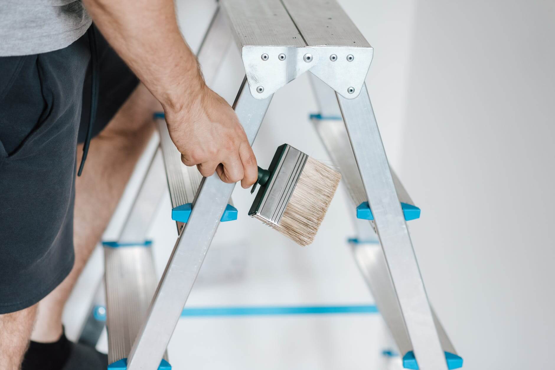 painter with brush climbing ladder during renovation work