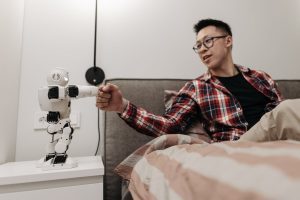 a man sitting on the bed while playing with the robot