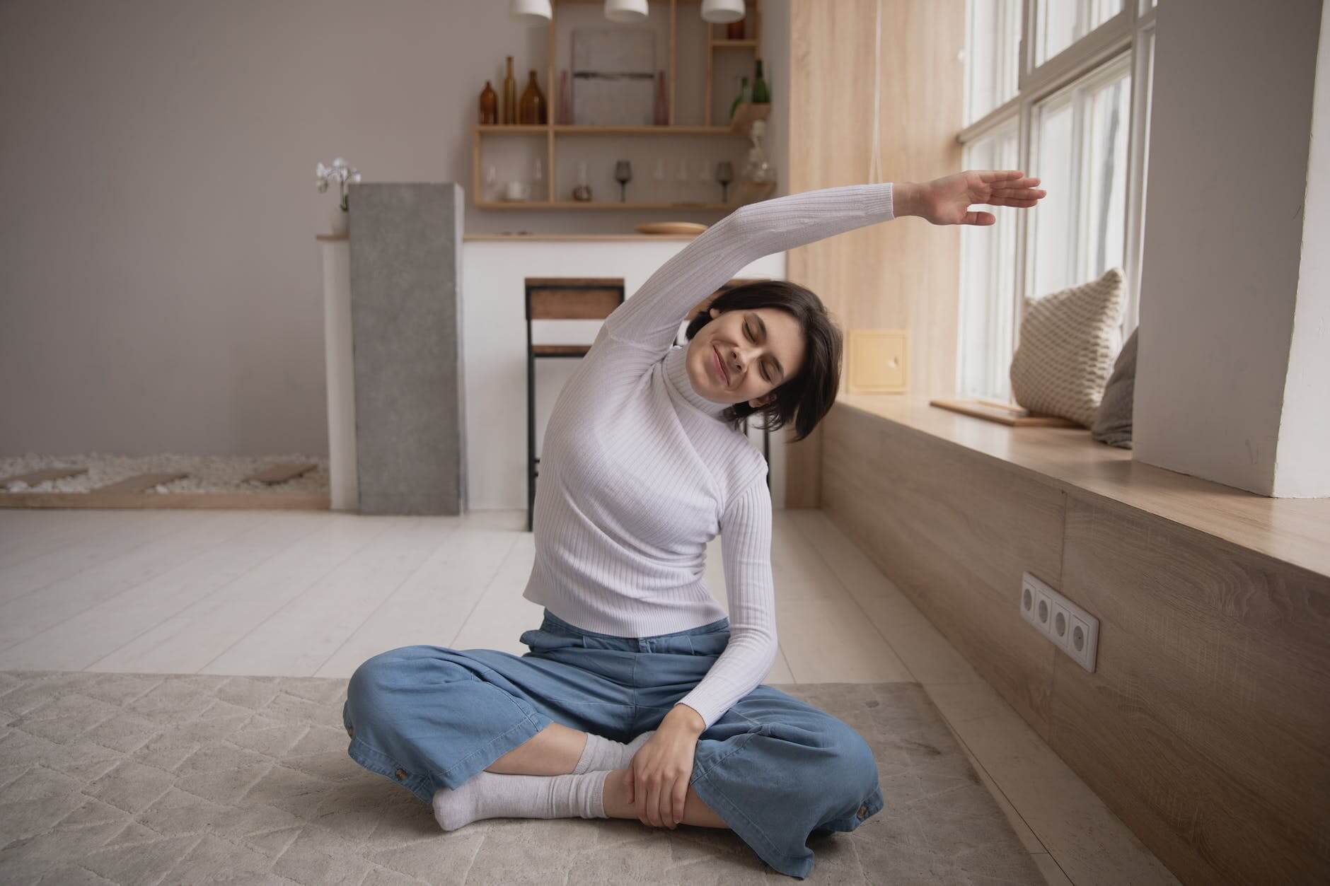 smiling woman practicing yoga with closed eyes at home