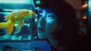 ethnic woman looking at fish in aquarium