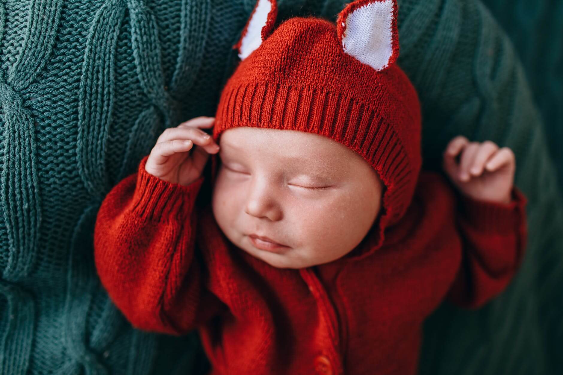 little tranquil baby in red woolen costume sleeping