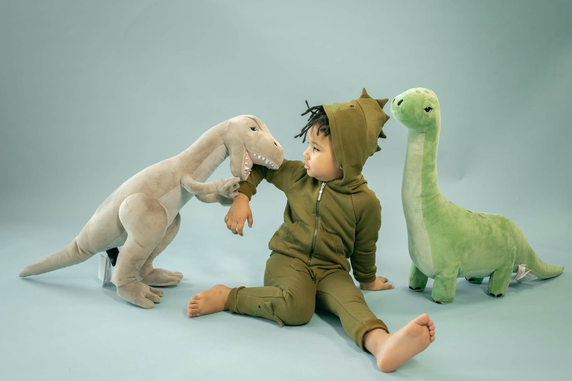black boy with toy dinosaurs on light background