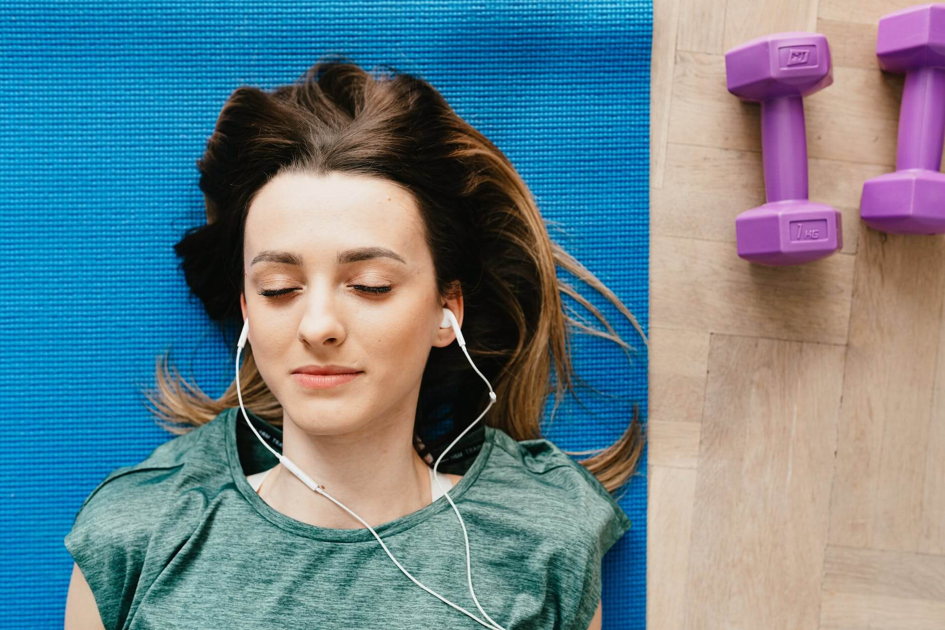 woman listening to music in earphones while resting after home workout